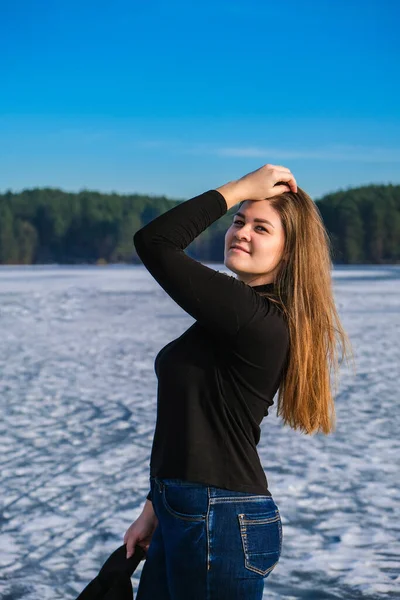 年轻的女性微笑着看着雪景中的相机 快乐的嬉皮士女孩与嘻哈温暖的冬季衣服 呆在冰冻的河里 年轻迷人的微笑女子冬季肖像 — 图库照片