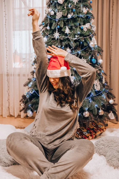 Noel Baba Şapkalı Güzel Genç Bir Kadın Noel Ağacı Süslüyor — Stok fotoğraf