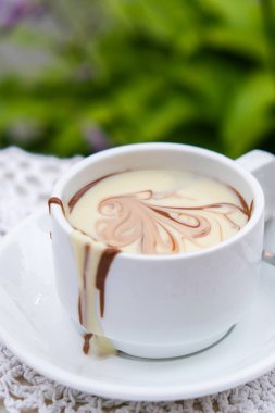 Yazın açık kafedeki masada sıcak çikolata kupası. Lokantada kahve ve kahvaltı zamanı. Çikolata, sıcak kaşlı süt, kakao. Sokak kafesi. Süt koyu çikolata.