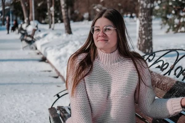 Krásná mladá žena v brýlích pletený svetr v zimním parku. Venku je chladno. Sníh šťastný úsměv portrét dívky — Stock fotografie