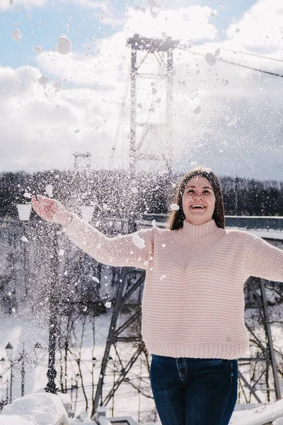 Різдво, свята та концепція сезону. Молода щаслива жінка дме сніг у зимовій лісовій природі. Теплий одяг в'язаний светр . — стокове фото