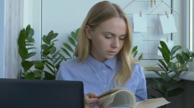 Genç bayan öğretmen masada oturuyor ve evde dizüstü bilgisayar kullanıyor. Okula dönüş kitabı okuyordum. Öğrenci çevrimiçi ders alıyor. Mesafe öğrenme. Sınav hazırlığı