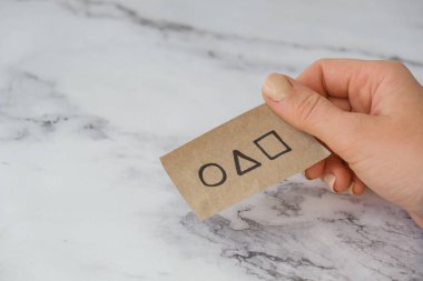 Kiev Ukrayna - Ekim 2021 Bir mürekkep balığı davetiyesi tutuyor. Mürekkep Balığı Oyun Kartı Ziyareti Sembolü. Çember, kare ve üçgen şekiller. Eğilimli Kalamar Oyunu Sembolü