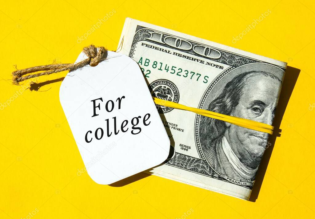 Dollars cash money in rubber band with text written note FOR COLLEGE. Concept of financial planning to save money for purpose of education. Save money today for future