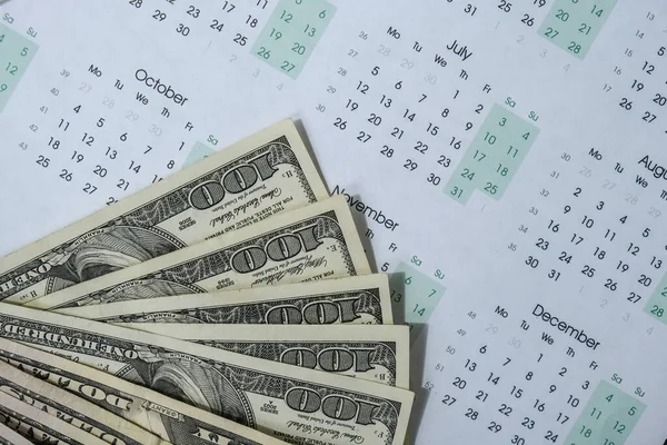 Ofis çalışma masasında dolar ve takvimle. Maaş için para sayıyorum. Yatırım tasarrufu. Ekonomi, ekonomi ve ev konsepti. Zenginlik ve refah finansmanı iş bütçesi. Çalışma alanı ofisi