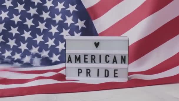 Sfondo con bandiera americana sventolata al rallentatore. Lightbox con testo AMERICAN PRIDE Bandiera degli Stati Uniti d'America. 4 luglio Giorno dell'Indipendenza. Festa nazionale del patriottismo degli Stati Uniti. Usa orgogliosi. — Video Stock