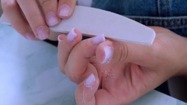 Kadın eli manikür yapıyor. Dosya ve şekil çivi bakımı, kişisel bakım. Evde otururken tek başına manikür yap. Diy. Manikür araçları