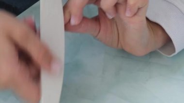 Kadın eli manikür yapıyor. Dosya ve şekil çivi bakımı, kişisel bakım. Evde otururken tek başına manikür yap. Diy. Manikür araçları