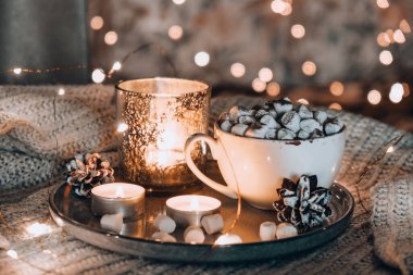 Sıcak kış kakaolu fincan ve yatakta marşmelov. Noel ışıkları. Çam kozalakları dekorasyonu. Sıcak kış günleri. Hygge.