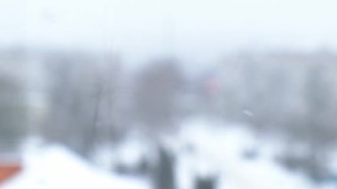 Yavaş yavaş kar yağıyor. Karla kaplı bir şehir ve yavaş çekimde uçan kar taneleri. Dikkati dağılmış. Seçici odaklanma. Bulanık kış arka plan soğuk hava