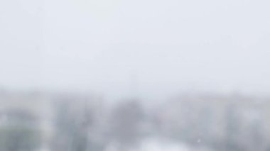 Yavaş yavaş kar yağıyor. Karla kaplı bir şehir ve yavaş çekimde uçan kar taneleri. Dikkati dağılmış. Seçici odaklanma. Bulanık kış arka plan soğuk hava