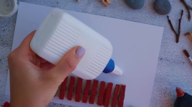 Çakıl taşları, deniz taşları, çamaşır mandalları ve beyaz arka planda dallardan oluşan kartpostalda Mutlu Noeller geyiği yapmak. Doğal Eko tarzı diy. Hediye fikri. Adım adım. Üst görünüm.