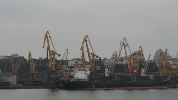 オデッサウクライナ- 2021年7月:グラブと海岸クレーンによるクリンカー貨物積載量の負荷下でのバルクキャリア船。海上貿易港活動。海上港のバルク貨物ターミナル。物流産業 — ストック動画
