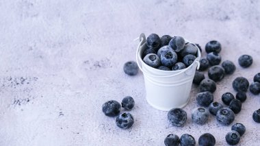 Donmuş yaban mersinleri beton arka planda küçük bir kovada. Sağlıklı organik mevsimlik meyve arka planı. Organik yiyecekler. Hasat, kış için yemek hazırlamak. Süper yemek. Güzel görüş. Gözlerini açık tut.