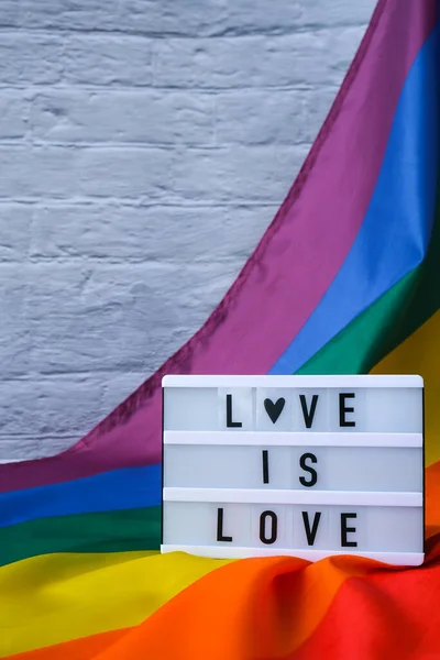 虹の旗とライトボックスとテキストの愛は愛です シルク素材で作られたレインボーLgbtqフラグ Lgbtqプライド月間のシンボル 平等な権利 平和と自由 Lgbtqコミュニティ — ストック写真