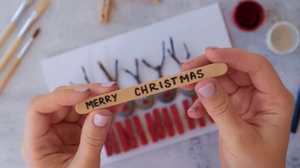 Making Diy Merry Christmas Hirsch auf Grußkarte Postkarte aus Kieselsteinen, Meeressteinen, Wäscheklammern und Zweigen auf weißem Hintergrund. Natürliche Öko-Stil diy. Geschenkidee. Schritt für Schritt. Ansicht von oben. — Stockvideo