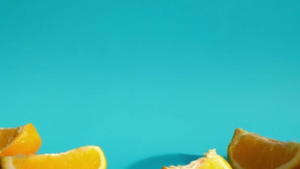 Vrouwelijke hand gezet en neem Glas vers persen Sinaasappelsap met gesneden vruchten op blauwe achtergrond. Vruchtensap, verse koude drank. Verfrissing in de zomer. Vruchten in tweeën gesneden — Stockvideo
