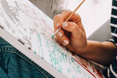 Tabloya numaralarla ve numaralandırılmış boya kavanozlarıyla resim yapmak. Kadın fırçayla resim çiziyor. Yaratıcı hobi. Yeni başlayanlar için resim yapmak. Evde kilitli kalmak için boş zaman aktivitesi, stres önleyici bir fikir. Meditasyon, rahatla.