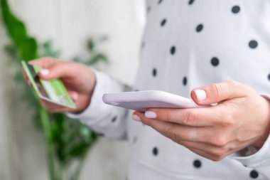 Kadının internet bankacılığı uygulamasını akıllı telefondan kullandığına ve bankamatik kartını evde tuttuğuna dair görüntüyü kapat. İnternetten alışveriş.