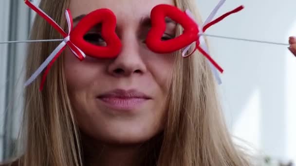 Young blonde girl in red sweater holding red hearts showing emotions. Video call. Valentines day. Love in distance. Stay home — Stock Video