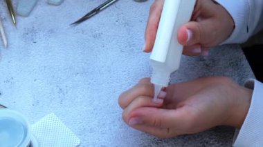 Kadın eli manikür yapıyor. Tırnak derisini söker, özen gösterir. Evde otururken tek başına manikür yap. Diy. Boya, dosya ve oval şekilli tırnaklar.