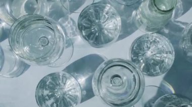 Güneş ışığında beyaz arka planda duran farklı güzel gözlükler gölgeler yaratır. Sert ışık, uzun gölgeler. Yaratıcı soyut içki konsepti, alkol kokteylleri. Cam kaplama konsepti