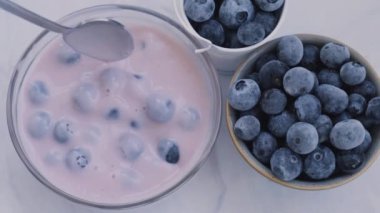 Masada yoğurt ve yabanmersinli kase. Yaban mersinli yoğurt yiyen bir kadın. Sağlıklı kahvaltı. Vejetaryen yemeği yiyen sağlıklı süper yiyecekler.