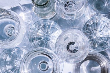 Güneş ışığında beyaz arka planda duran farklı güzel gözlükler gölgeler yaratır. Sert ışık, uzun gölgeler. Yaratıcı içki konsepti, alkol kokteyli. Cam kaplama konsepti. Geometrik şekiller