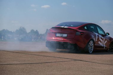 Kiev Ukrayna Temmuz 2021 Tesla Electric araba kiremitleri üzerinde rakamlar yapar. E-Sür. Elektrikli araç kullanıyor. Kırmızı araba lastik dumanı içinde daireler çiziyor. Lastik patladı.