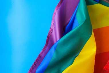 Mavi arka planda gökkuşağı bayrağı ve kopyalama alanı. İpek kumaştan yapılmış gökkuşağı lgbtq bayrağı. LGBTQ gurur ayının sembolü. Eşit haklar. Barış ve özgürlük. LGBTQ topluluğunu destekle