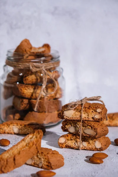 Traditional Italian cantuccini cookies with almonds in glass jar. Sweet dried biscuits. Homemade fresh Italian cookies cantuccini stacks and organic almond seeds. Healthy organic eating nutrition