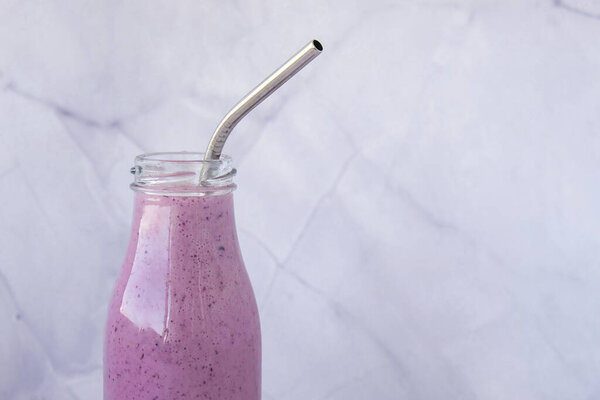 Blueberry smoothie topped with blueberries. A glass of breakfast protein smoothie drink made from pureed raw blueberries, banana, milk, yogurt, and cottage cheese. Vegetarian vegan food