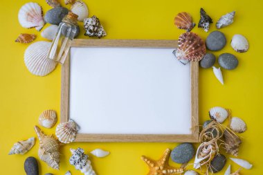 Fotokopi alanı, deniz kabukları, çakıl taşları, sarı arka plan için kompozisyon çerçevesi. Boşluk, üst görünüm, durgun hayat, düzlük. Deniz seyahati konsepti turizm ve tatil beldeleri. Yaz tatili