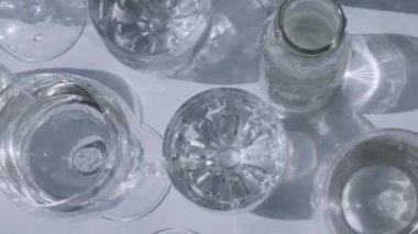 Güneş ışığında beyaz arka planda duran farklı güzel gözlükler gölgeler yaratır. Sert ışık, uzun gölgeler. Yaratıcı soyut içki konsepti, alkol kokteylleri. Cam kaplama konsepti