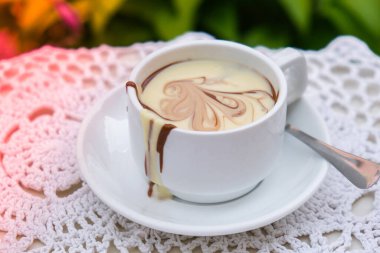 Yazın açık kafedeki masada sıcak çikolata kupası. Lokantada kahve ve kahvaltı zamanı. Çikolata, sıcak kaşlı süt, kakao. Sokak kafesi. Süt koyu çikolata.