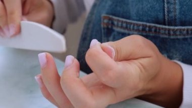 Kadın eli manikür yapıyor. Dosya ve şekil çivi bakımı, kişisel bakım. Evde otururken tek başına manikür yap. Diy. Manikür araçları