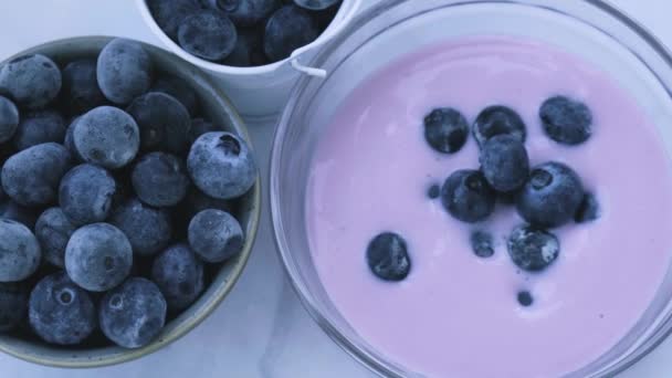 Ciotola con yogurt e mirtilli in tavola. Donna che mangia yogurt ai mirtilli con mirtilli freschi. Colazione sana. Super cibo mangiare sano vegetariano cibo vegano — Video Stock