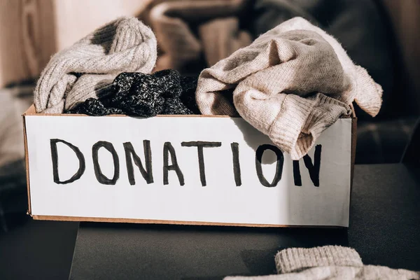 Donationslåda med gamla begagnade kläder inomhus. Glad välgörenhet. Vinterkläder i pappkartong. Donation eller återvinning av kläder — Stockfoto