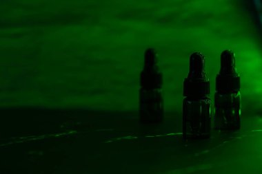 CBD yağlı çeşitli cam şişeler, THC tentür. Vape konsepti. Işık efektleri. Şişesinde yağ özü olan tıbbi esrarlar. Sağlık hizmetleri kavramı
