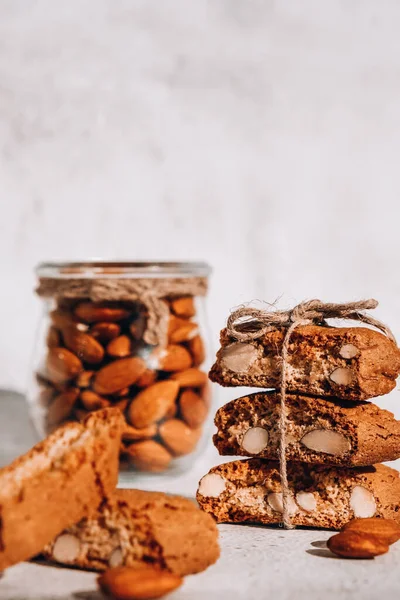 Traditional Italian cantuccini cookies with almonds in glass jar. Sweet dried biscuits. Homemade fresh Italian cookies cantuccini stacks and organic almond seeds. Healthy organic eating