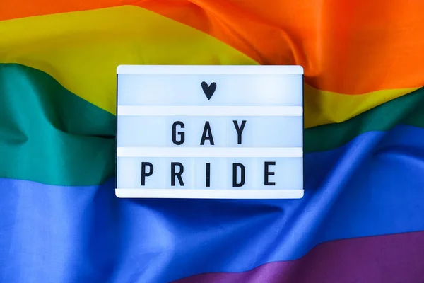 ライトボックスとテキストGAY PRIDEとレインボーフラグ。シルク素材で作られたレインボーlgbtqフラグ。LGBTQプライド月間のシンボル。平等な権利。平和と自由 — ストック写真