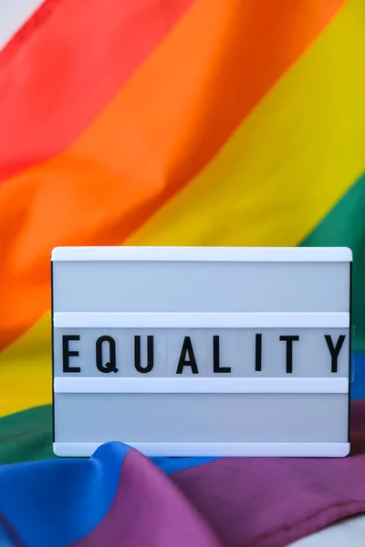 Tęczowa flaga ze światłem i tekstem JAKOŚĆ. Tęczowa flaga Igbtq wykonana z jedwabiu. Symbol miesiąca dumy LGBTQ. Równe prawa. Pokój i wolność — Zdjęcie stockowe