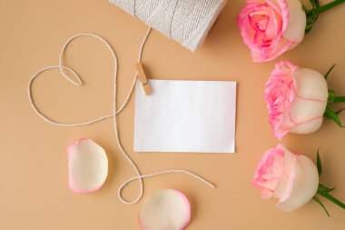 Bej arka planda kalp şeklinde beyaz pamuk ipli yumuşak pembe güller. Boş kağıt nota kopyalama alanı en az trend bileşimi. Tarafsız toprak tonları. Sevgililer Günü Anneleri için tebrik kartı.