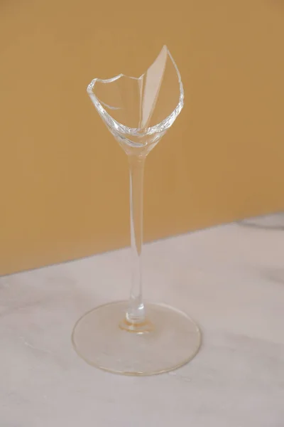 Broken champagne glass on minimal beige background. Creative art concept. After Party The concept of danger fight against alcoholism, drunkenness and refusal of alcohol. — Stock Photo, Image