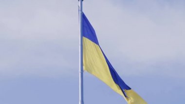 Ukrayna ulusal bayrağı mavi gökyüzüne karşı rüzgarda dalgalanıyor. Ukrayna halkının ulusal sembolü - mavi ve sarı bayrak rüzgarda dalgalanıyor.