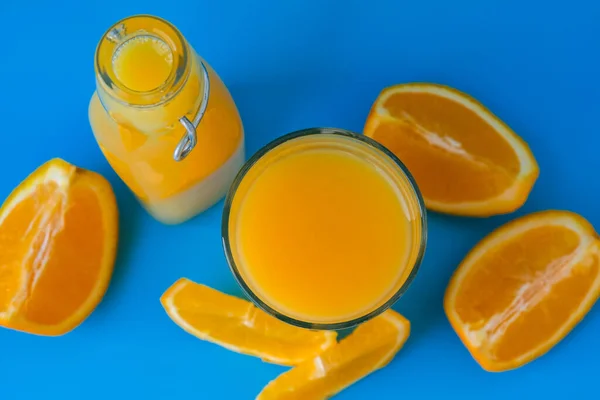 Стеклянная Бутылка Свежего Апельсинового Сока Нарезанными Фруктами Синем Фоне Фруктовый — стоковое фото