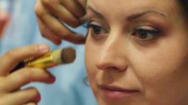 Makyaj sanatçısı genç bir kadının gözlerine makyaj yapar. Geline makyaj yapan profesyonel bir makyöz. Yabani ot