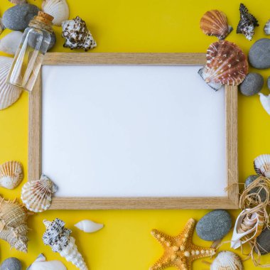 Fotokopi alanı, deniz kabukları, çakıl taşları, sarı arka plan için kompozisyon çerçevesi. Boşluk, üst görünüm, durgun hayat, düzlük. Deniz seyahati konsepti turizm ve tatil beldeleri. Yaz tatili