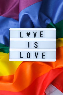 Işıkkutusu ve mesajı olan gökkuşağı bayrağı aşktır. İpek kumaştan yapılmış gökkuşağı lgbtq bayrağı. LGBTQ gurur ayının sembolü. Eşit haklar. Barış ve özgürlük. LGBTQ topluluğunu destekle