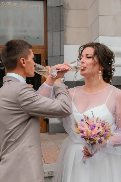 Braut und Bräutigam halten Hochzeitsgläser mit Champagner. Frisch verheiratet feiern. Schöne Couleur — Stockfoto